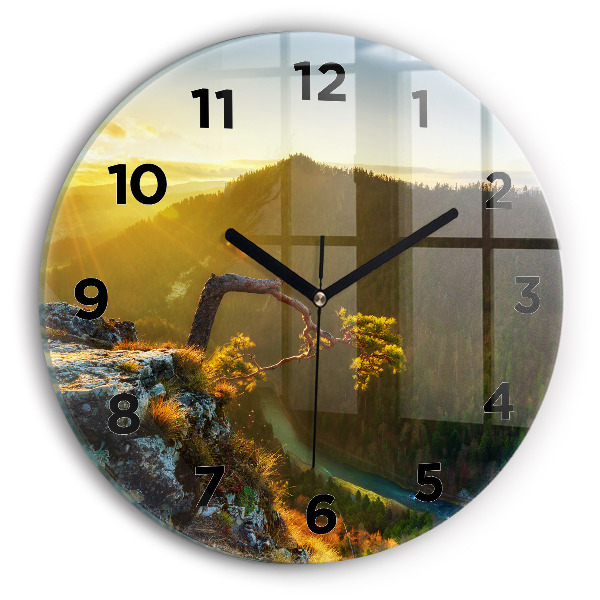 Round glass clock Sunset over the mountains
